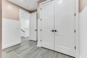 A hallway with white doors, a wooden floor, and a beige wall. - Nashville-themed house with rooftop bar & game room, sleeps 12 near Geodis Park (Nashville)