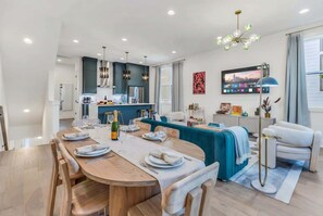 A modern kitchen with a dining area, a sofa, and a TV. - Nashville-themed house with game room, sleeps 12, near Geodis Park (Nashville)
