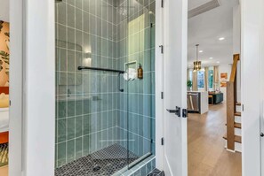A modern bathroom with a glass shower enclosure, a towel rack, and a visible toilet paper holder.