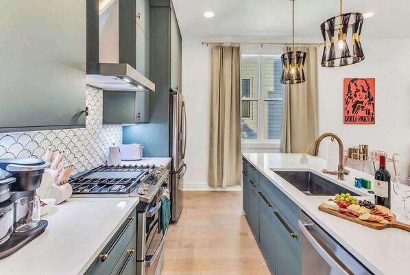 A modern kitchen with a gas stove, oven, and a large island with a sink and countertop.