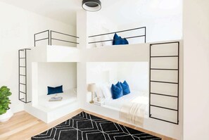 A multi-level bunk bed room with a ladder, a bedside table with a lamp, and a geometric rug. - Fall getaway: 2 rooftop homes with fire pits, sleeps 20, near The Gulch (Nashville)