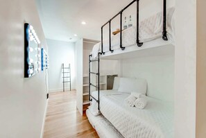 Habitación con literas, un tocador con espejo y repisas con botellas.