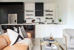 A modern living space with a kitchen, a sofa, a coffee table, and a bar area. - Two rooftop-deck homes near The Gulch, Nashville | sleeps 20 across 6 bedrooms (Nashville)