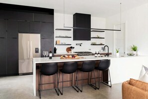 Una cocina moderna con una isla central, taburetes de bar y un horno empotrado.