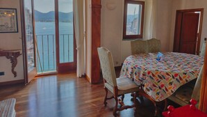 A room with a bed, a chair, a table, a window with a view of the sea, and a balcony.