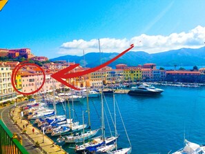 A marina with boats docked, a waterfront promenade, and colorful buildings in the background.