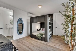 A modern bedroom with a built-in bed, a mirror, a bedside table, and a plant. - Nashville house with hot tub, game room & pool table near Geodis Park (Nashville)