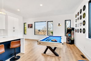 Ein zeitgemäßer Wohnbereich mit Billardtisch, Bar und Spielautomaten.