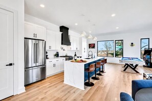 A modern kitchen with white cabinetry, stainless steel appliances, and a central island with bar stools.