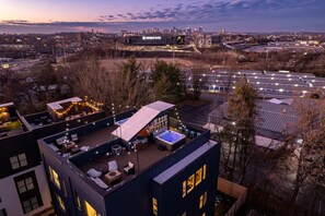 Une terrasse sur le toit équipée d’un jacuzzi, d’un espace salon et de guirlandes lumineuses.