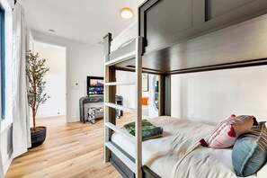 A modern bedroom with a bunk bed, a potted plant, and a cityscape view.
