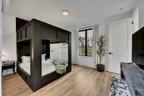 A modern bedroom with a bunk bed, a desk, a potted plant, and a TV. - Fall getaway hot tub & game room house sleeps 12 near Geodis Park, Nashville (Nashville)