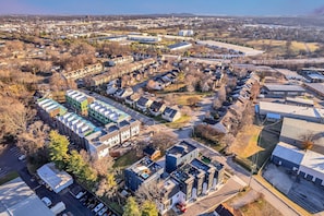 Vue aérienne d’un quartier résidentiel avec des maisons modernes, un parking et un grand bâtiment industriel.
