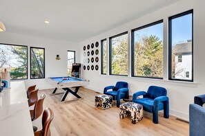 A modern living room with a pool table, blue chairs, and a wall of vinyl records.