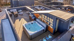 A rooftop terrace with a hot tub, seating areas, and a mural.