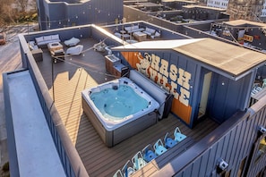 Una terraza en la azotea con jacuzzi, zonas de estar y un mural.