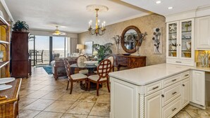 A spacious kitchen with a large island, white cabinetry, and a dining area with a round table and chairs. - Breathtaking Views - 7th Floor Beachfront Condo - Tennis, Basketball, Shuffleboard, Elevator, Pool (Navarre)