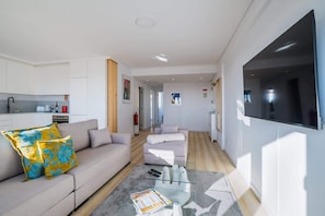 Un salon moderne avec un canapé, une table basse en verre et un téléviseur à écran plat.