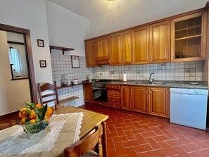 A kitchen with wooden cabinets, a tiled backsplash, and a dining area with a table set for two.