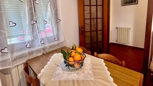 A dining area with a table set for two, a window with heart-shaped decorations, and a door leading to another room. - Villino Rita a Portoferraio (Portoferraio)