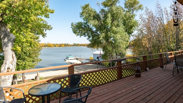 Una terraza de madera con asientos exteriores y vistas a un lago.