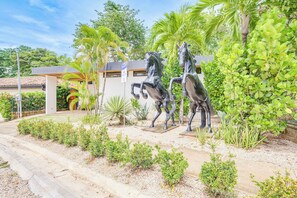 Una propiedad con entrada pavimentada, un patio cubierto y una estatua de caballos.