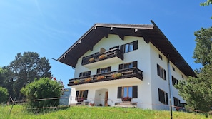 A two-story building with balconies, a wooden facade, and a clear sky.