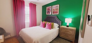 A bedroom with a bed, a nightstand, a lamp, and two framed pictures on the wall.