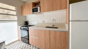A kitchen with wooden cabinets, a microwave, a sink, and a stove. - Modern apartment in Recoleta near Recoleta Mall (Buenos Aires)