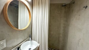 A bathroom with a round mirror, a sink, a shower, and a patterned floor. - Modern apartment in Recoleta near Recoleta Mall (Buenos Aires)