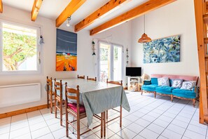 Un espace repas comprenant une table et des chaises, un canapé et des œuvres d’art accrochées aux murs.