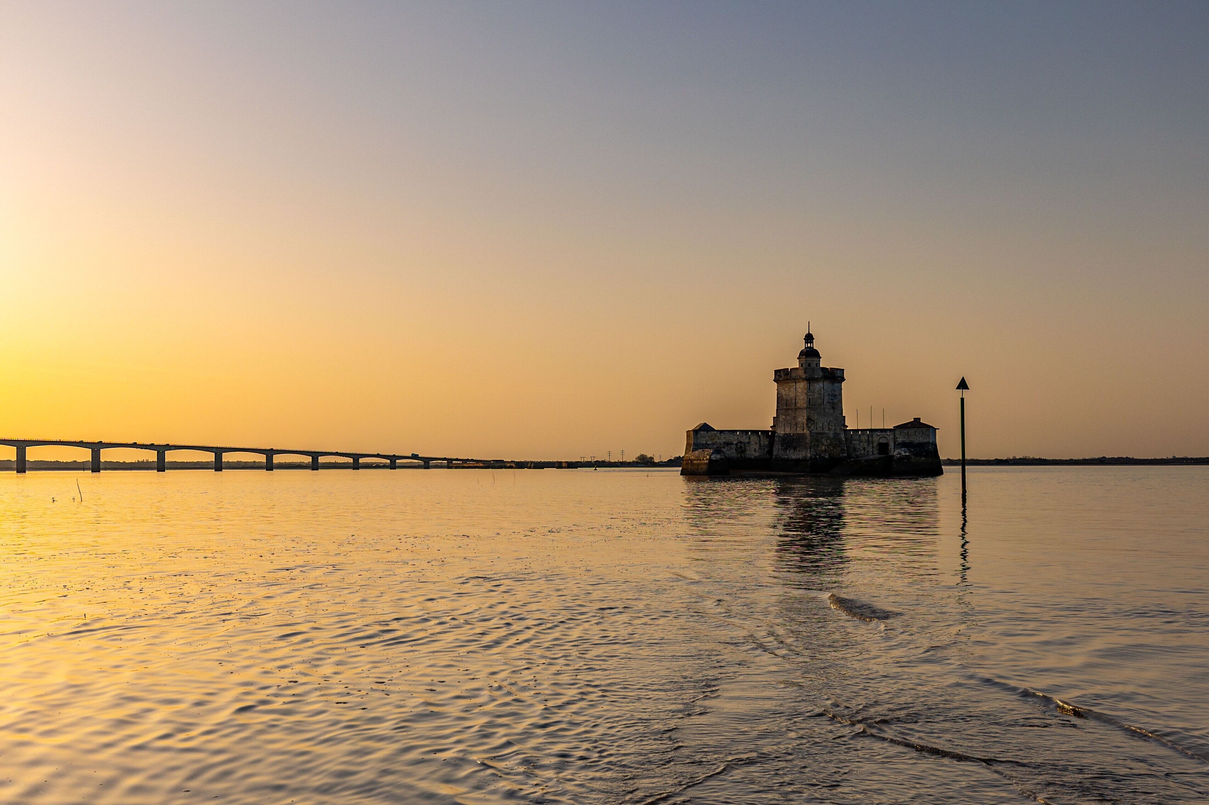 Un phare au bord de l’eau, au coucher du soleil.