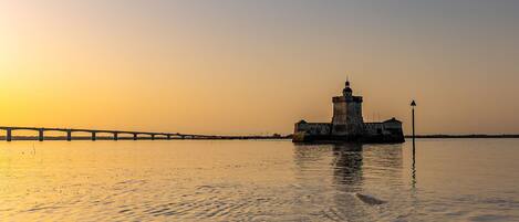 Un phare au bord de l’eau, au coucher du soleil.