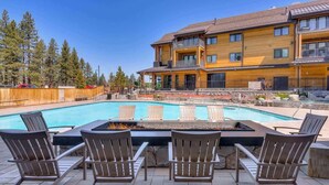A pool with lounge chairs and a fire pit, surrounded by a wooden fence and a building with balconies. - Luxury @Heavenly Village, with Pool+Hot Tub+Games (South Lake Tahoe)