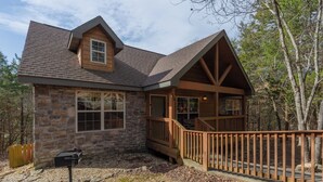 Une maison en pierre avec une terrasse en bois et une cheminée en pierre.