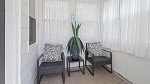 Una habitación con dos sillas, una mesita y una planta en maceta.