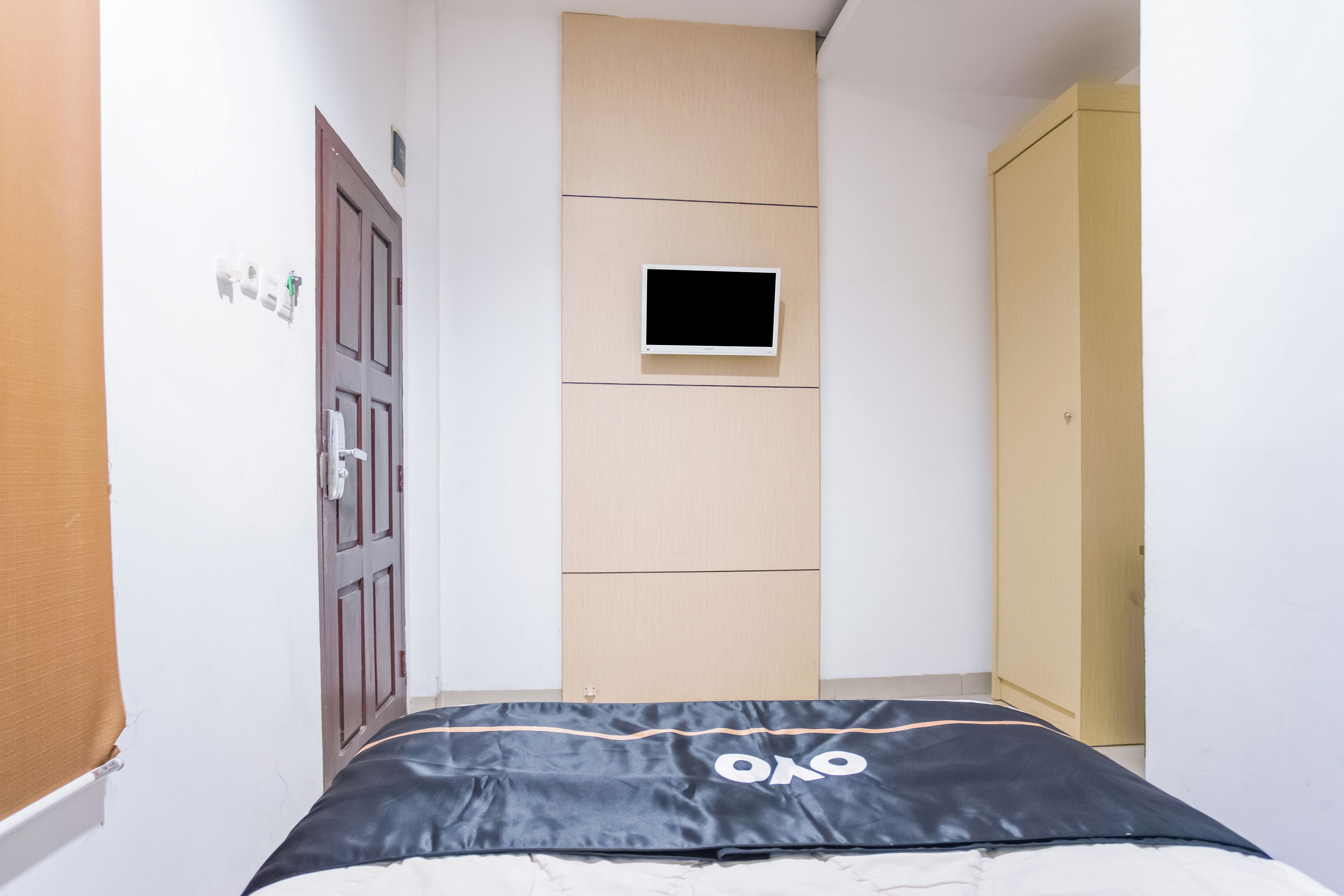 A narrow room with a bed, a small window, and a wardrobe.