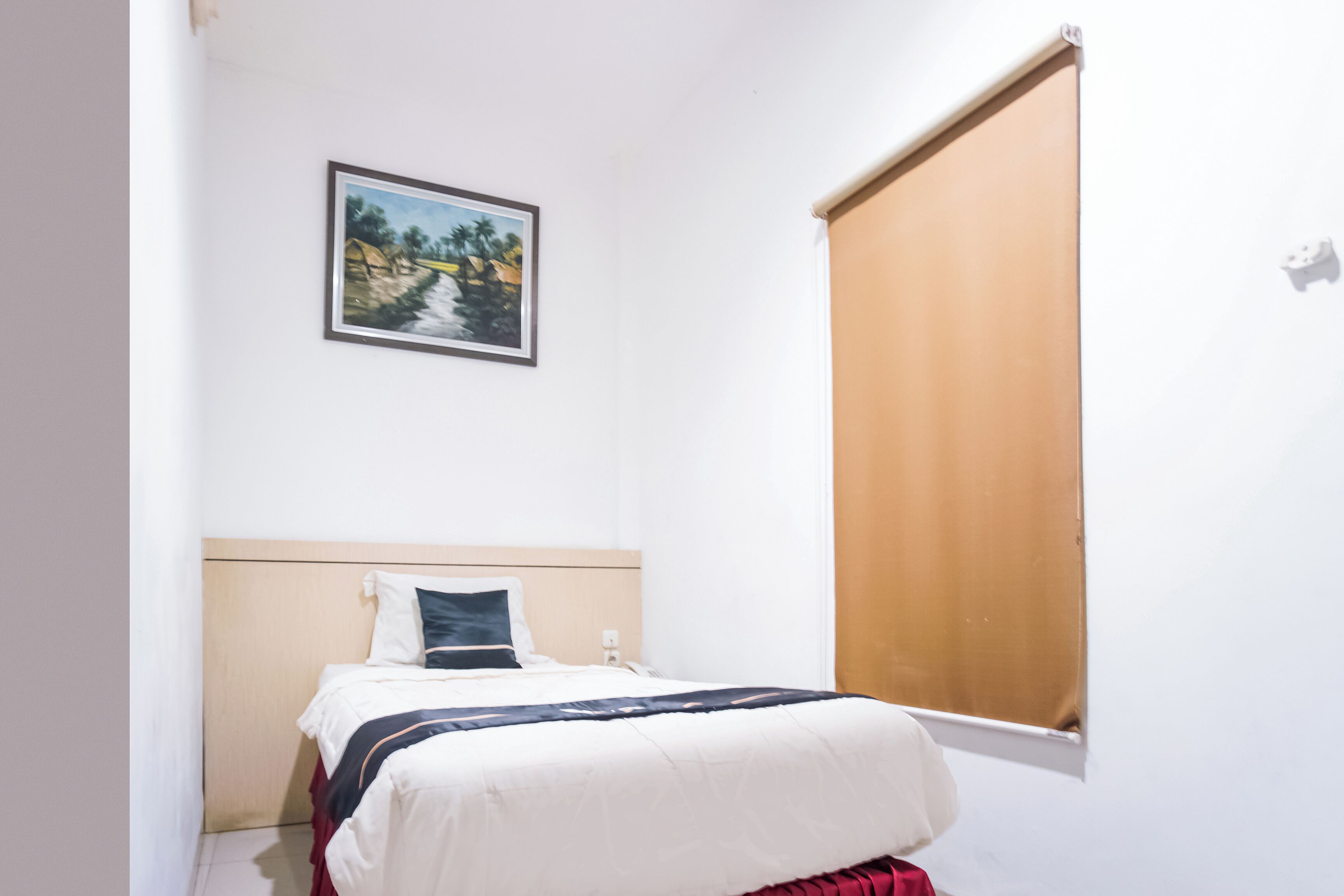 Una camera da letto con un letto, una finestra con persiana e un quadro appeso al muro.