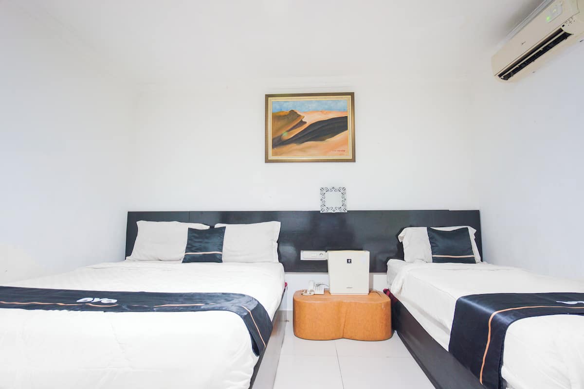 A hotel room with two beds, a mounted air conditioner, a framed painting on the wall, and a guitar on the floor.