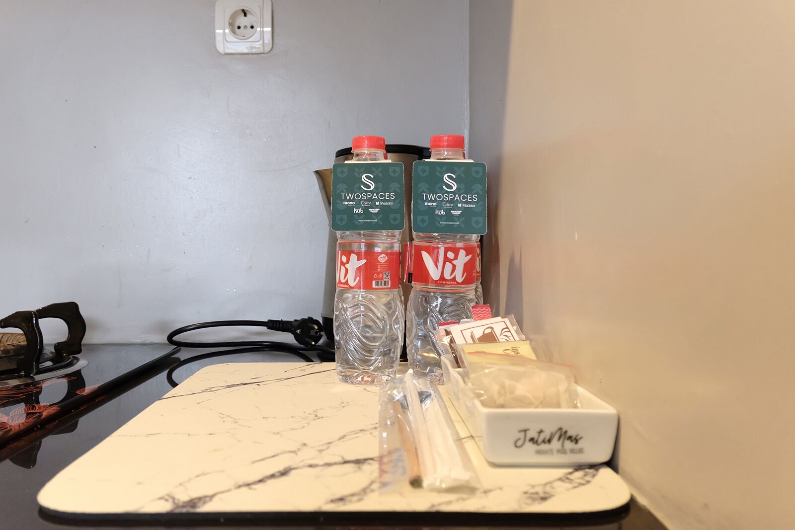 Une table avec deux bouteilles d’eau, une petite boîte étiquetée « Jatid Mas » et quelques articles dans un sac en plastique.
