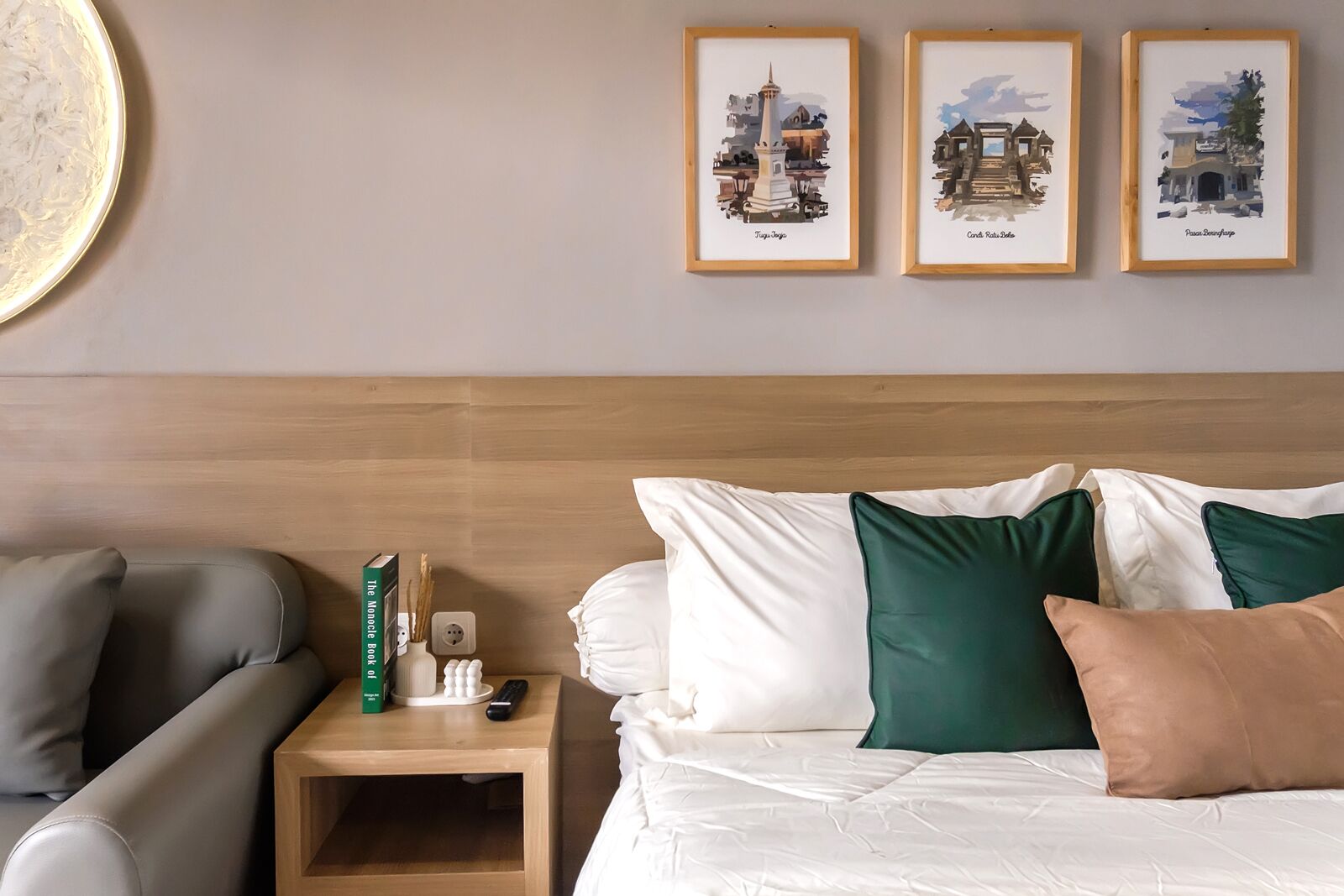 A hotel room with a bed, a nightstand, a lamp, a book, and framed pictures on the wall.