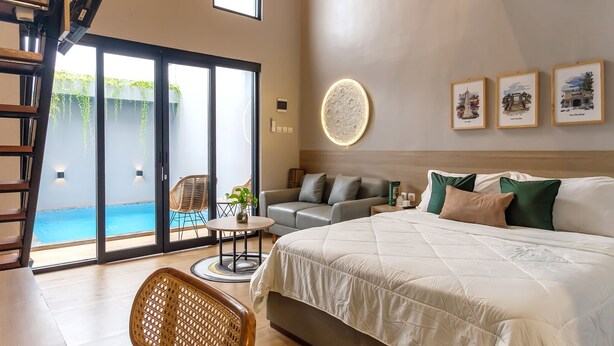 Et soveværelse med en stor seng, en sofa, et spisebord og udsigt til et udendørs swimmingpool.