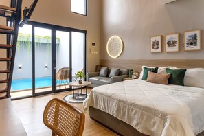 A bedroom with a large bed, a sofa, a dining table, and a view of an outdoor swimming pool. - Calma Jatimas Klayar Villa Sleman Jogja (Berbah)