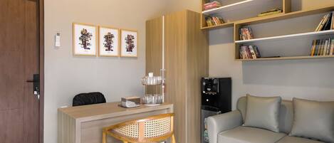 A compact living space with a desk, chair, sofa, and built-in shelving with books.