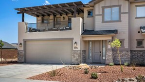 A modern two-story house with a covered balcony, a garage, and a stone facade. - Luxury 5BR Wellness Retreat w/ Private Pool, Hot Tub & Cold Plunge Near Zion (Hurricane)