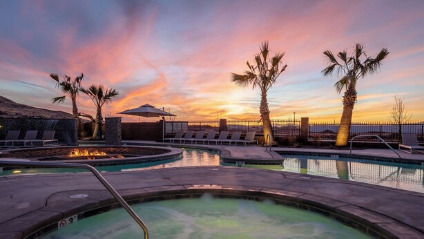 A pool area with lounge chairs and a hot tub, surrounded by palm trees and a sunset view. - Luxury 5BR Wellness Retreat w/ Private Pool, Hot Tub & Cold Plunge Near Zion (Hurricane)