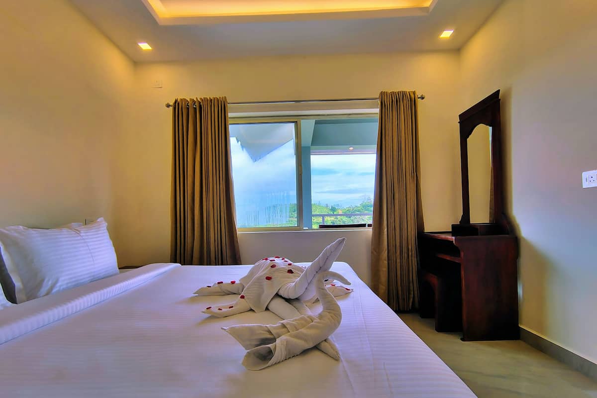 A hotel room with a large bed, a window with curtains, a wooden dresser, and a mirror on the wall.