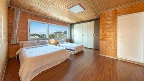 A bedroom with two beds, wooden flooring, a large window, and a wardrobe. - Yeosu La Rosa Private Pool Villa Pension (Yeosu)