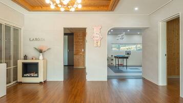 A modern interior with a wooden floor, a fireplace, a wall-mounted clock, and a basketball hoop.