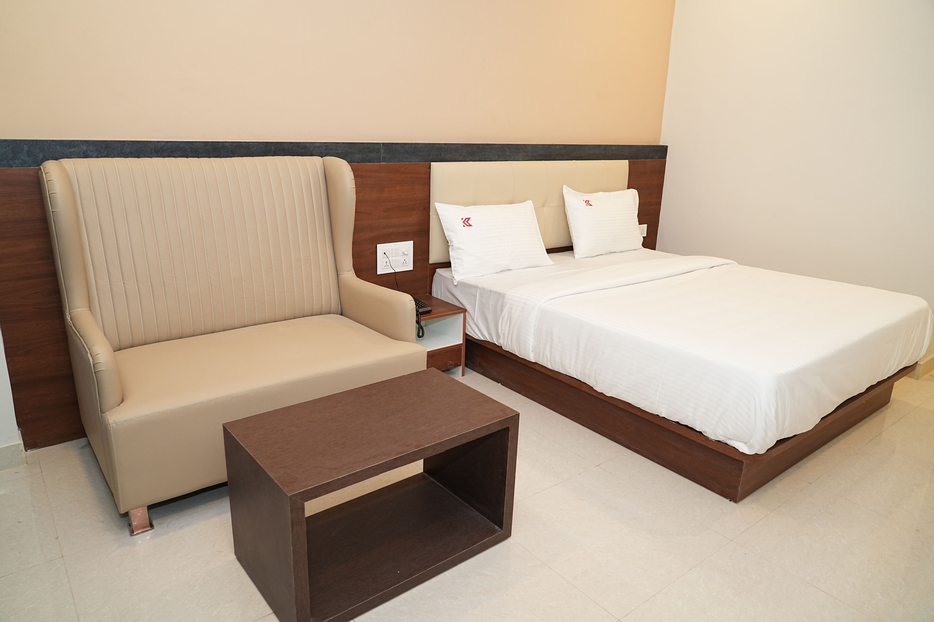 A hotel room with a bed, a sofa, and a small table.